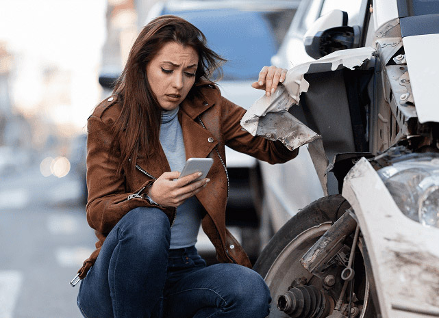 Young sad woman texting after car crash