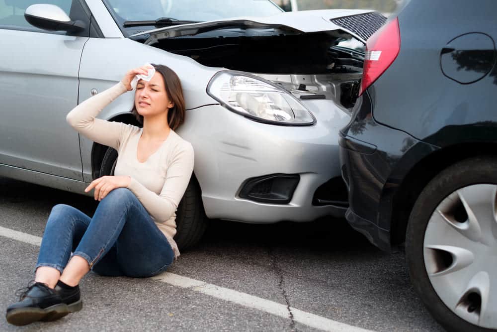 A girl sitting down after an accident and holding her head